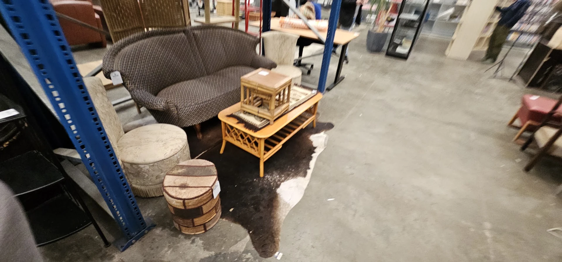 Tweedehands meubels en woonaccessoires uitgestald in de kringloopwinkel, waaronder een grijze fauteuil, bamboe salontafel en 