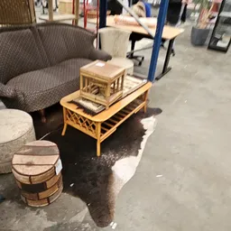 Tweedehands meubels en woonaccessoires uitgestald in de kringloopwinkel, waaronder een grijze fauteuil, bamboe salontafel en 