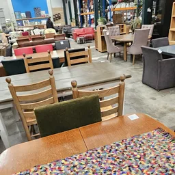 Winkelinterieur met houten stoelen met groene zitting, houten tafels en meubels, stellingen met dozen op de achtergrond