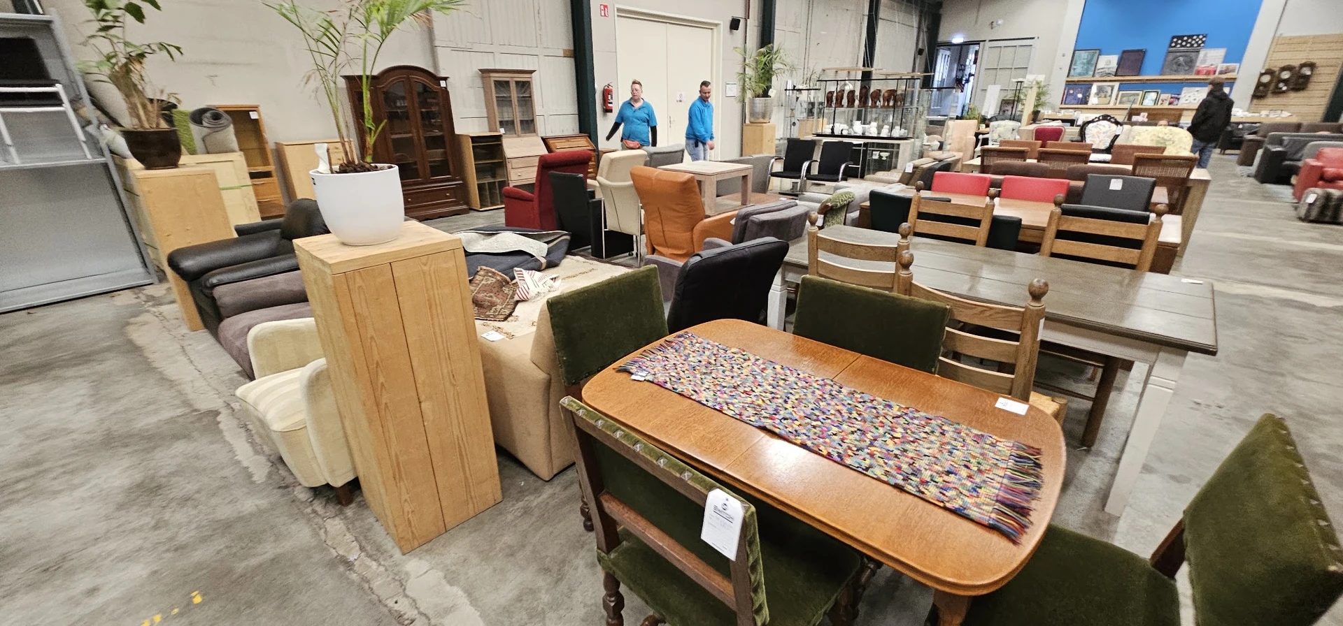 Winkelhal met diverse meubelen en huishoudartikelen uitgestald, personeel op de achtergrond