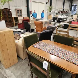 Winkelhal met diverse meubelen en huishoudartikelen uitgestald, personeel op de achtergrond
