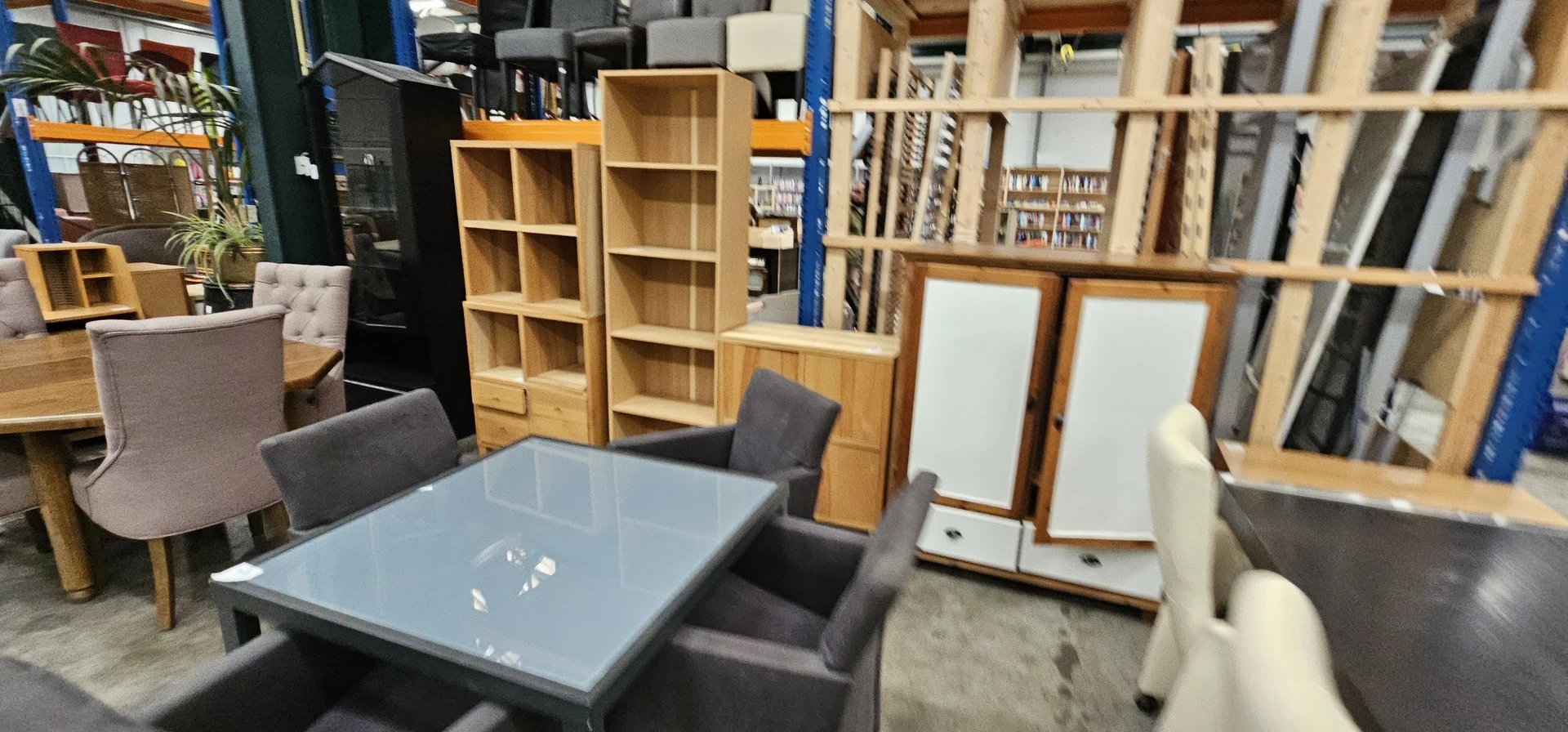 Winkelvloer met houten kasten, tafels en stoelen in een kringloopwinkel