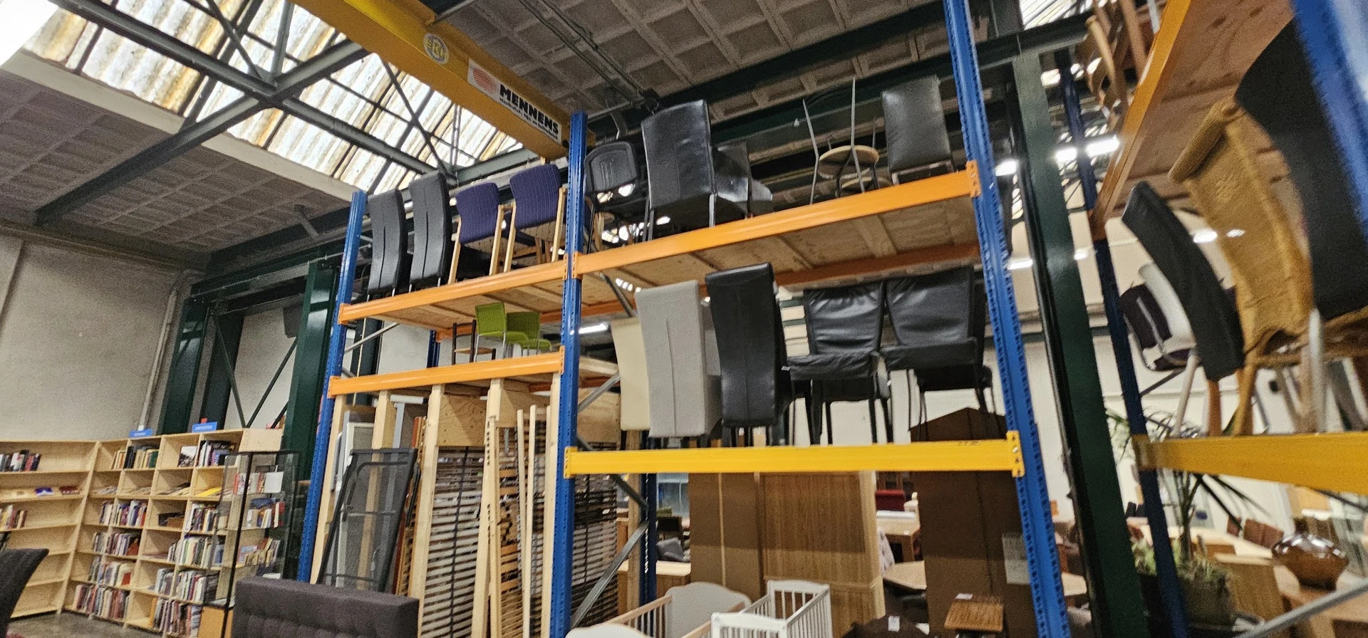 Stellingen met diverse tweedehands artikelen waaronder speakers, elektronica en huishoudelijke spullen in een kringloopwinkel