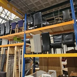 Stellingen met diverse tweedehands artikelen waaronder speakers, elektronica en huishoudelijke spullen in een kringloopwinkel