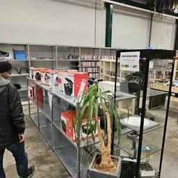 Winkelrek met rode verpakte elektronicaartikelen, boeken en een plant ertegenaan