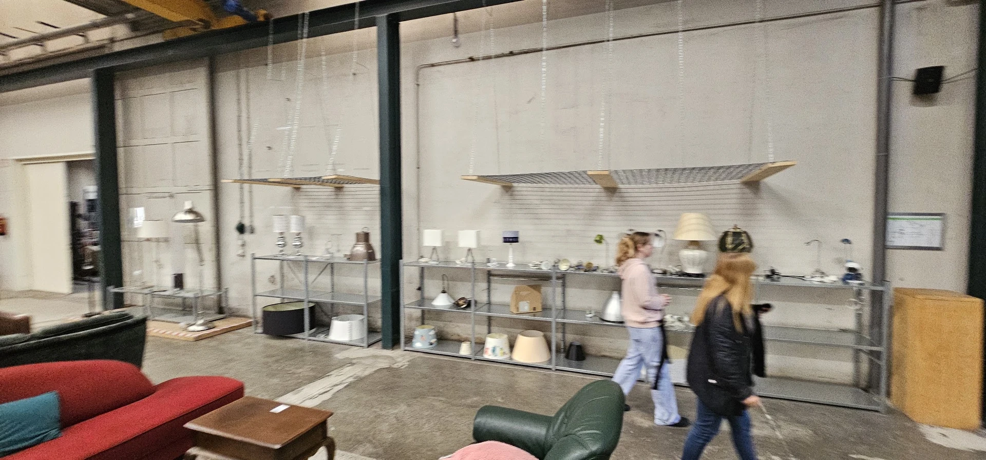 Winkelvloer met meubels en stellingen vol serviesgoed en huishoudspullen in kringloopwinkel