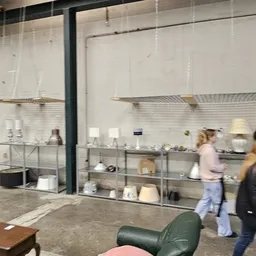 Winkelvloer met meubels en stellingen vol serviesgoed en huishoudspullen in kringloopwinkel