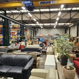 Winkelvloer met zitmeubels en meubels, stellingen op de achtergrond, industrieel plafond met overhead-kraan