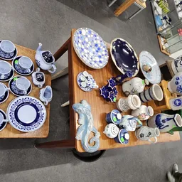Tweedehands servies en tafelgerei met blauwe decoratie uitgestald op houten tafels