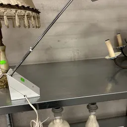 Close-up van een grijs metalen tafelblad met witte zijkant en montagebeugel