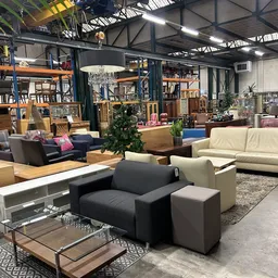 Ruim winkelinterieur met diverse zitmeubels, kasten en inrichtingsobjecten, breed overzicht van de vloer