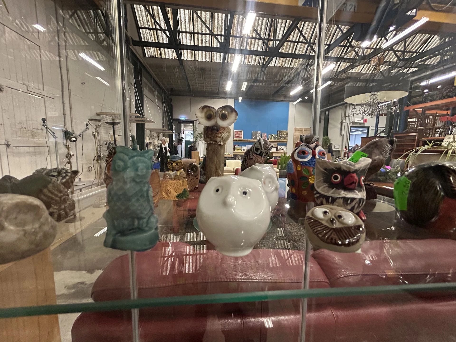 Uitgestalde decoratieve items en beelden in een vitrinekasten, waaronder keramische en stenen figuren