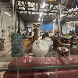 Uitgestalde decoratieve items en beelden in een vitrinekasten, waaronder keramische en stenen figuren