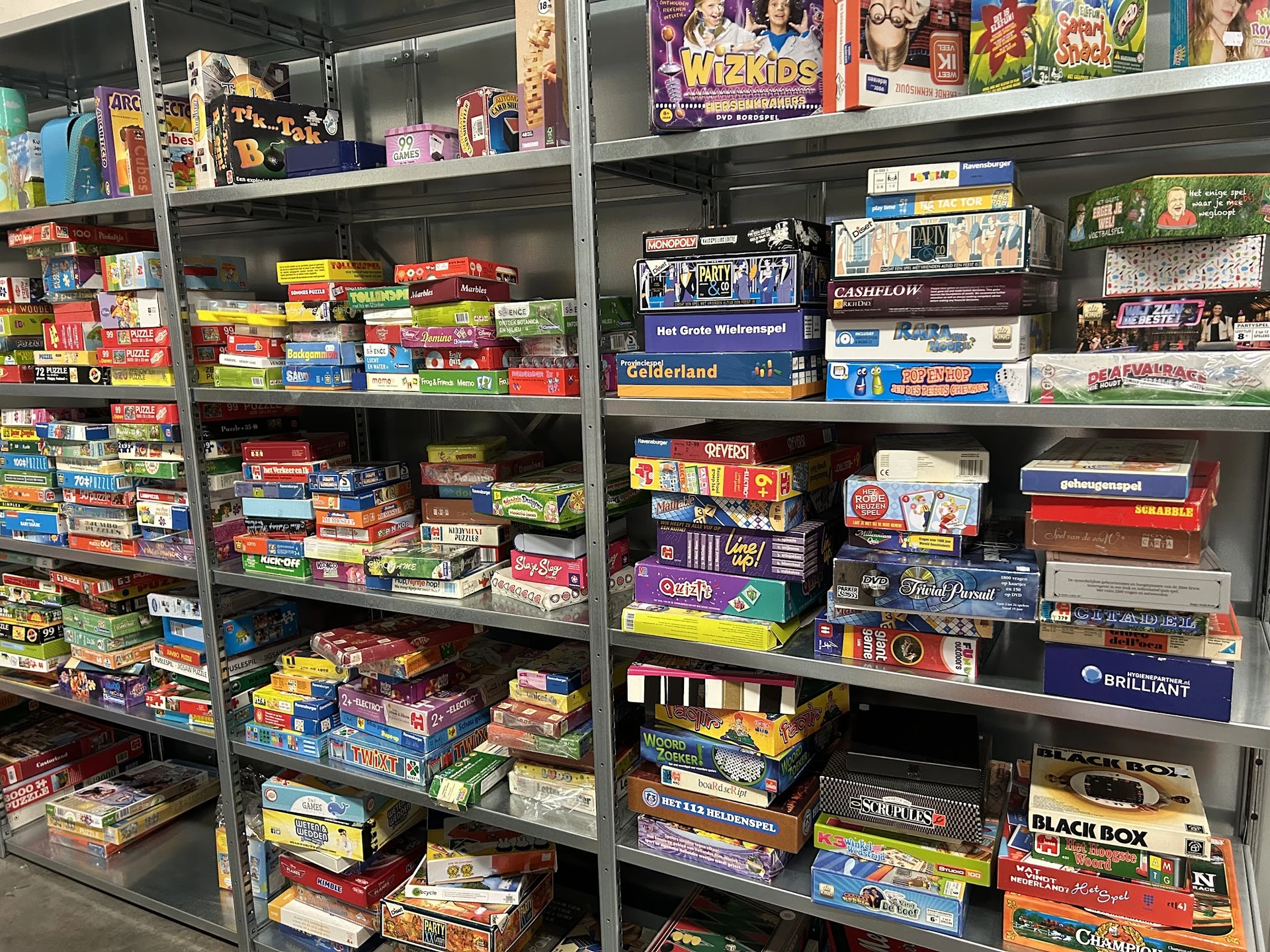 Stellingen vol met tweedehands bordspellen en spellen in gekleurde dozen
