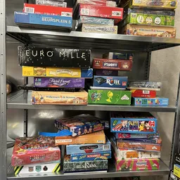 Stellingkast met uitgestalde gezelschapsspellen en bordspellen, waaronder Euromille, Trivial Pursuit en andere titels