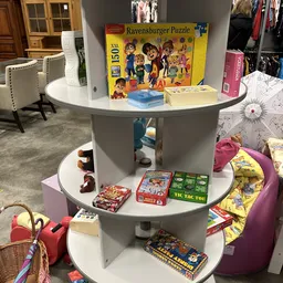 Ronde kast met meerdere niveaus vol speelgoed, bordspellen en kinderartikelentop winkelvloer