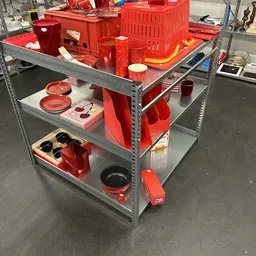 Stellingkast met rood serviesgoed en keukengerei, waaronder borden, pannen en rode plastic bakken