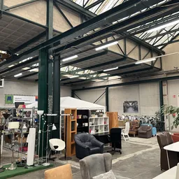 Overzicht van de winkelvloer met meubels, huishoudapparatuur en diverse spullen onder een stalen dakestructuur