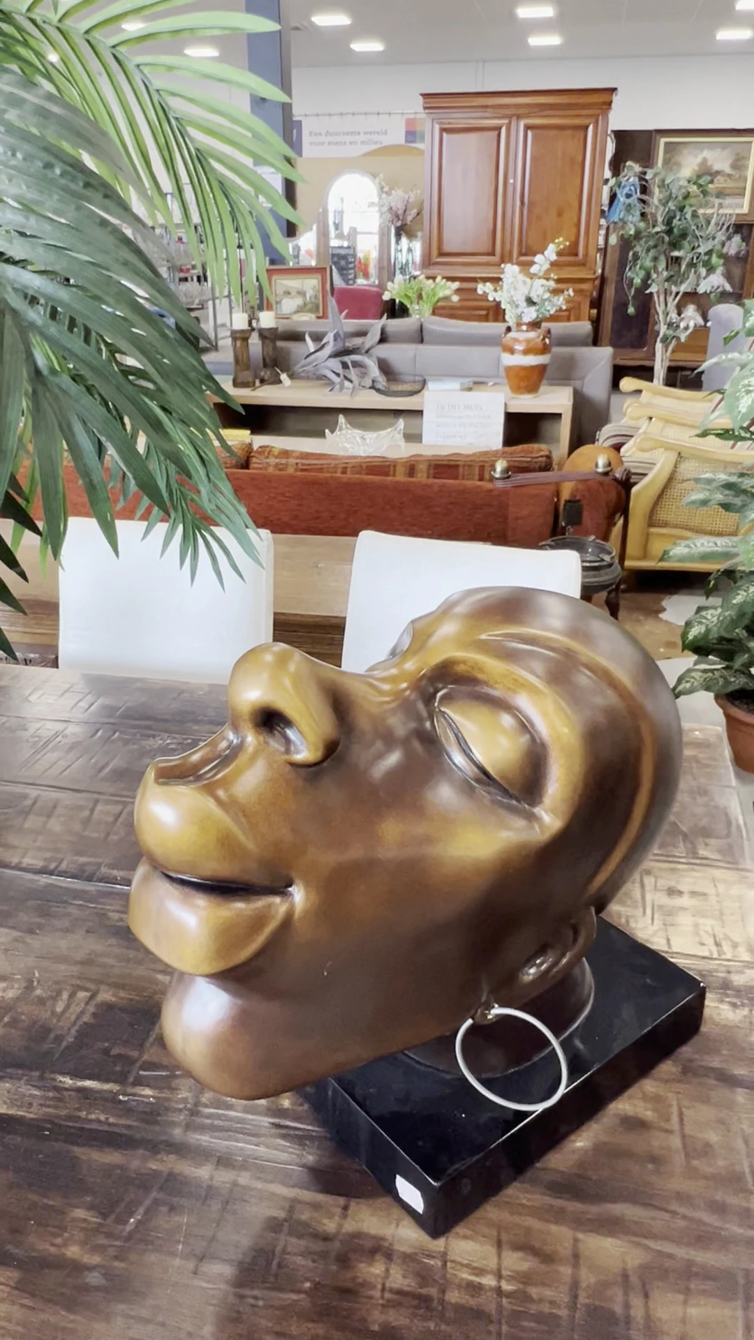 Goudkleurig bronzen borstbeeld van een man op houten tafel in de winkel
