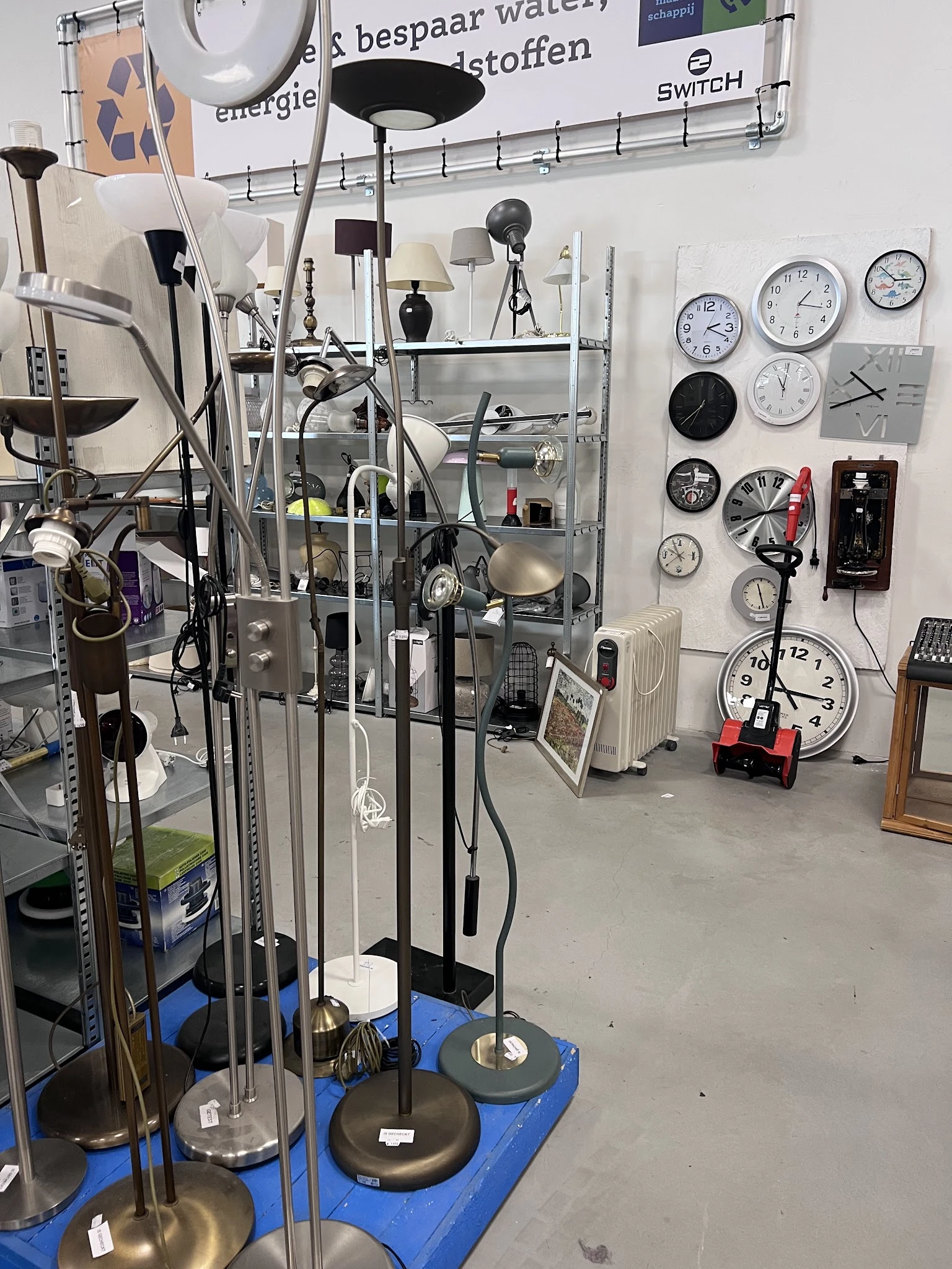 Winkelinterieur met stellingen, diverse huishoudapparatuur, klokken en spullen uitgestald