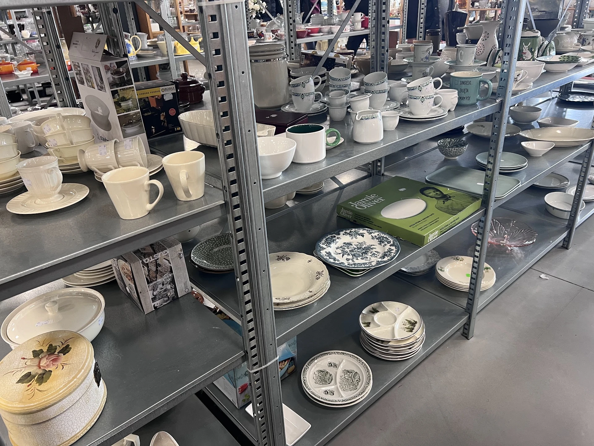 Stellingen met wit serviesgoed zoals borden, kopjes en schalen netjes uitgestald
