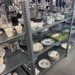 Stellingen met wit serviesgoed zoals borden, kopjes en schalen netjes uitgestald