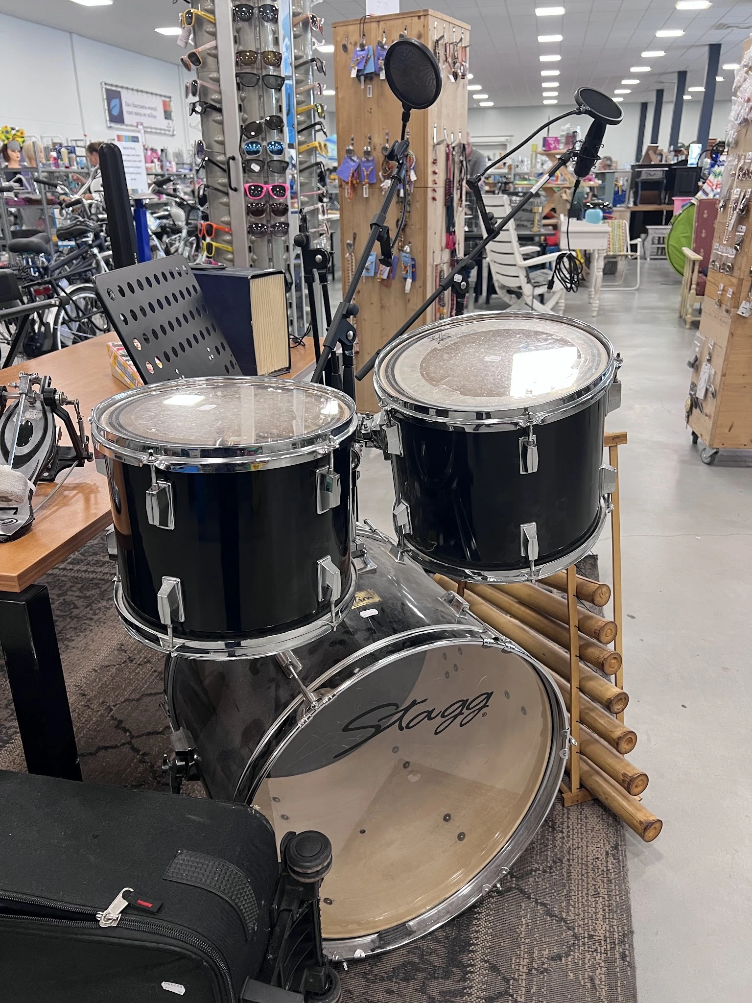 Drie zwarte drums met metallic snaredrum op houten standaard in de winkel