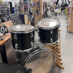 Drie zwarte drums met metallic snaredrum op houten standaard in de winkel