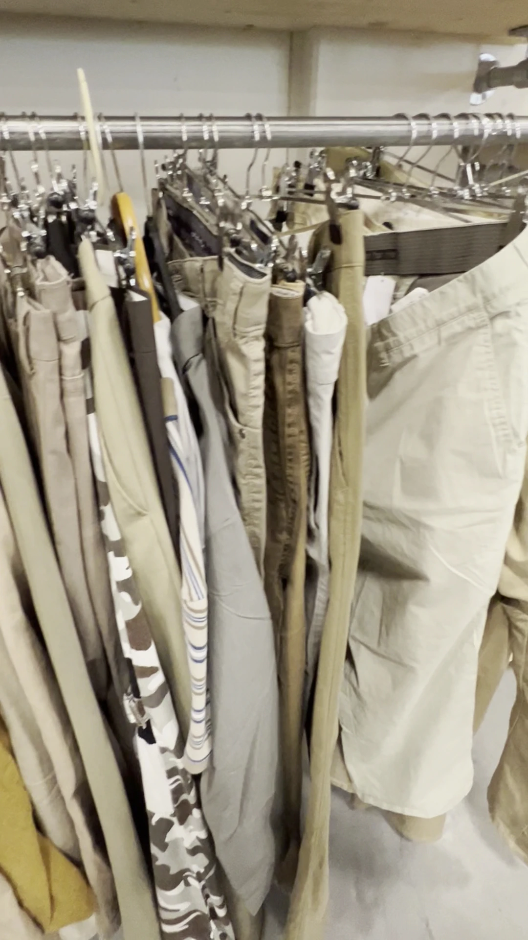 Rekken met tweedehands broeken en pantalons in beige, wit en taupe tinten