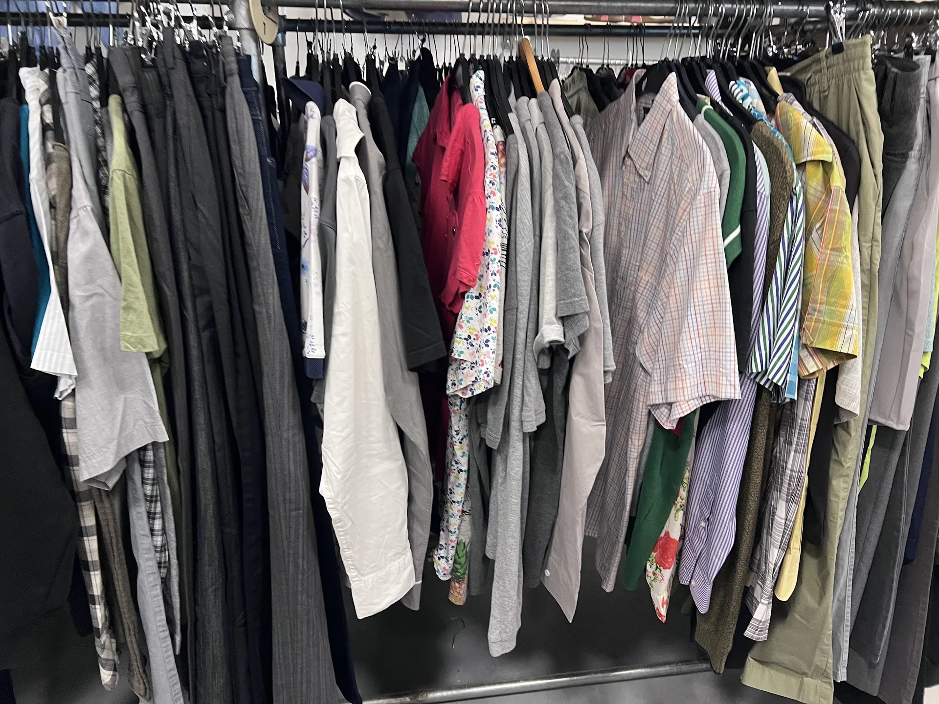 Rekken met tweedehands kleding in diverse kleuren en stijlen