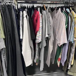 Rekken met tweedehands kleding in diverse kleuren en stijlen