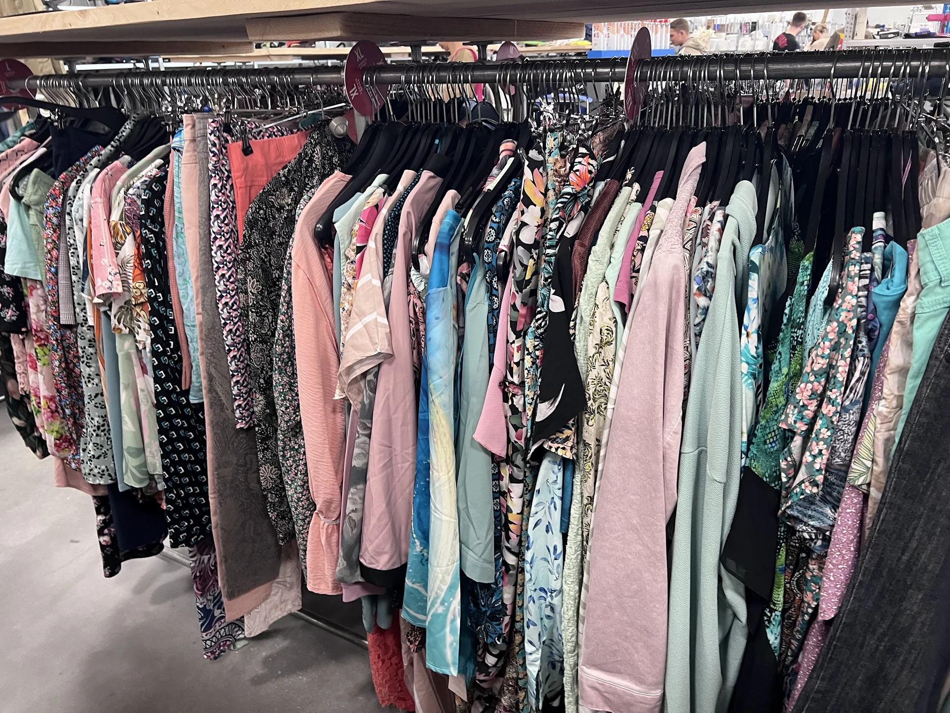 Rekken met tweedehands dameskleding in verschillende kleuren en patronen