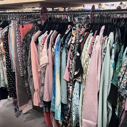 Rekken met tweedehands dameskleding in verschillende kleuren en patronen