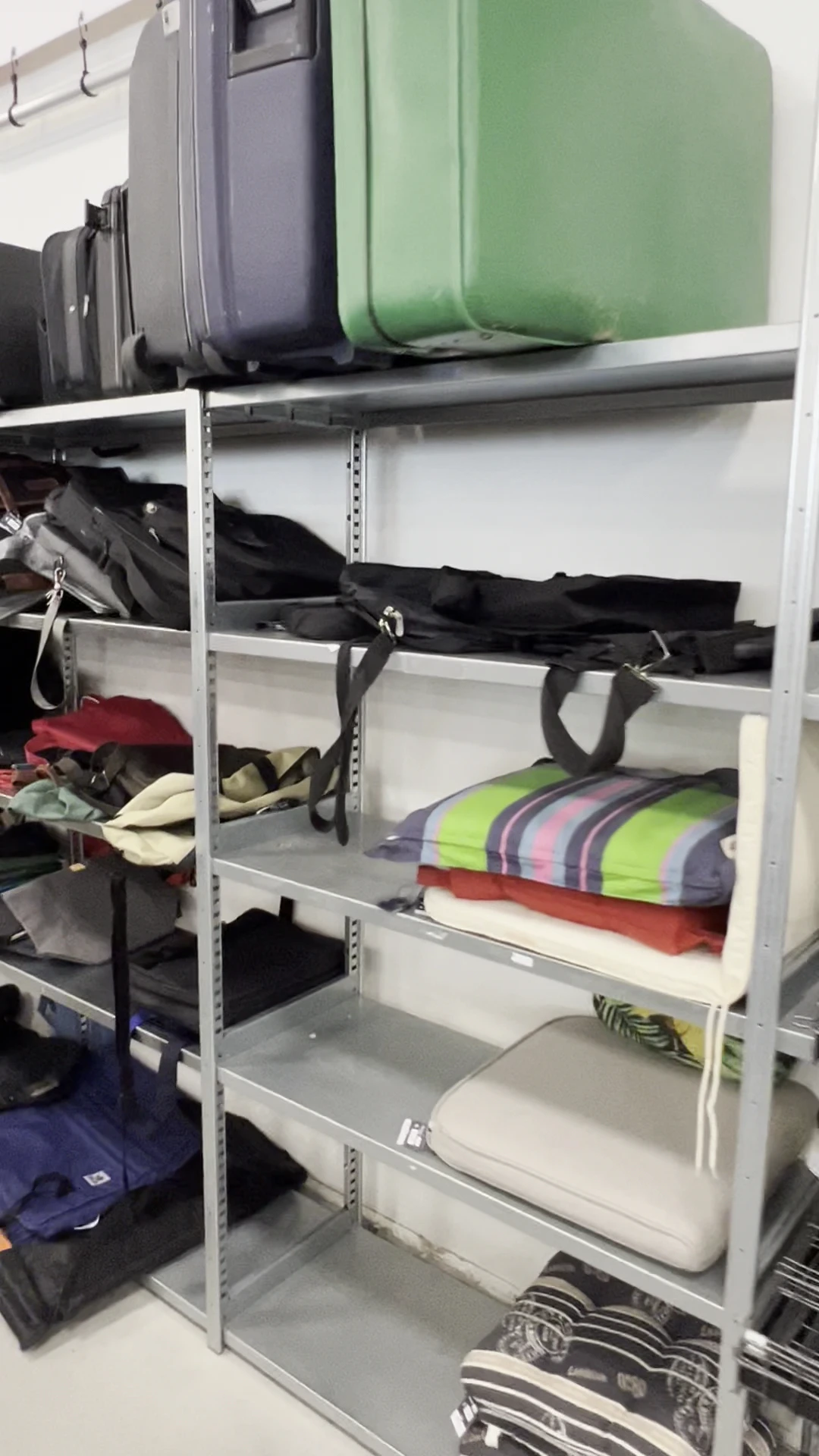 Metalen stellingen met tweedehands kleding en tassen in verschillende kleuren