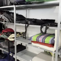 Metalen stellingen met tweedehands kleding en tassen in verschillende kleuren
