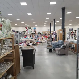Ruime winkelvloer met meubels, decoratie, kleding en diverse tweedehands artikelen op stellingen en rekken