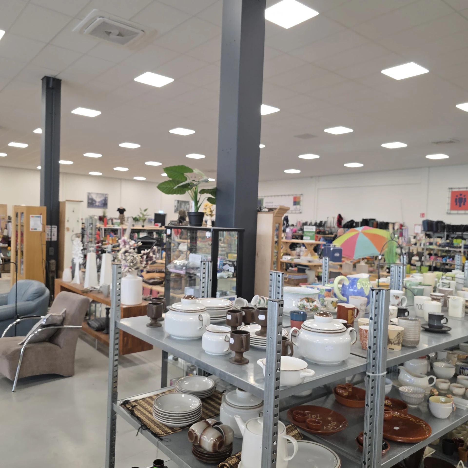 Stellingen met servies, kopjes, kannen en huishoudelijke artikelen in de kringloopwinkel