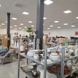 Stellingen met servies, kopjes, kannen en huishoudelijke artikelen in de kringloopwinkel