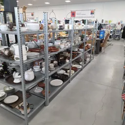 Metalen stellingen vol met serviesgoed, pannen, schalen en ander keukengerei in de kringloopwinkel