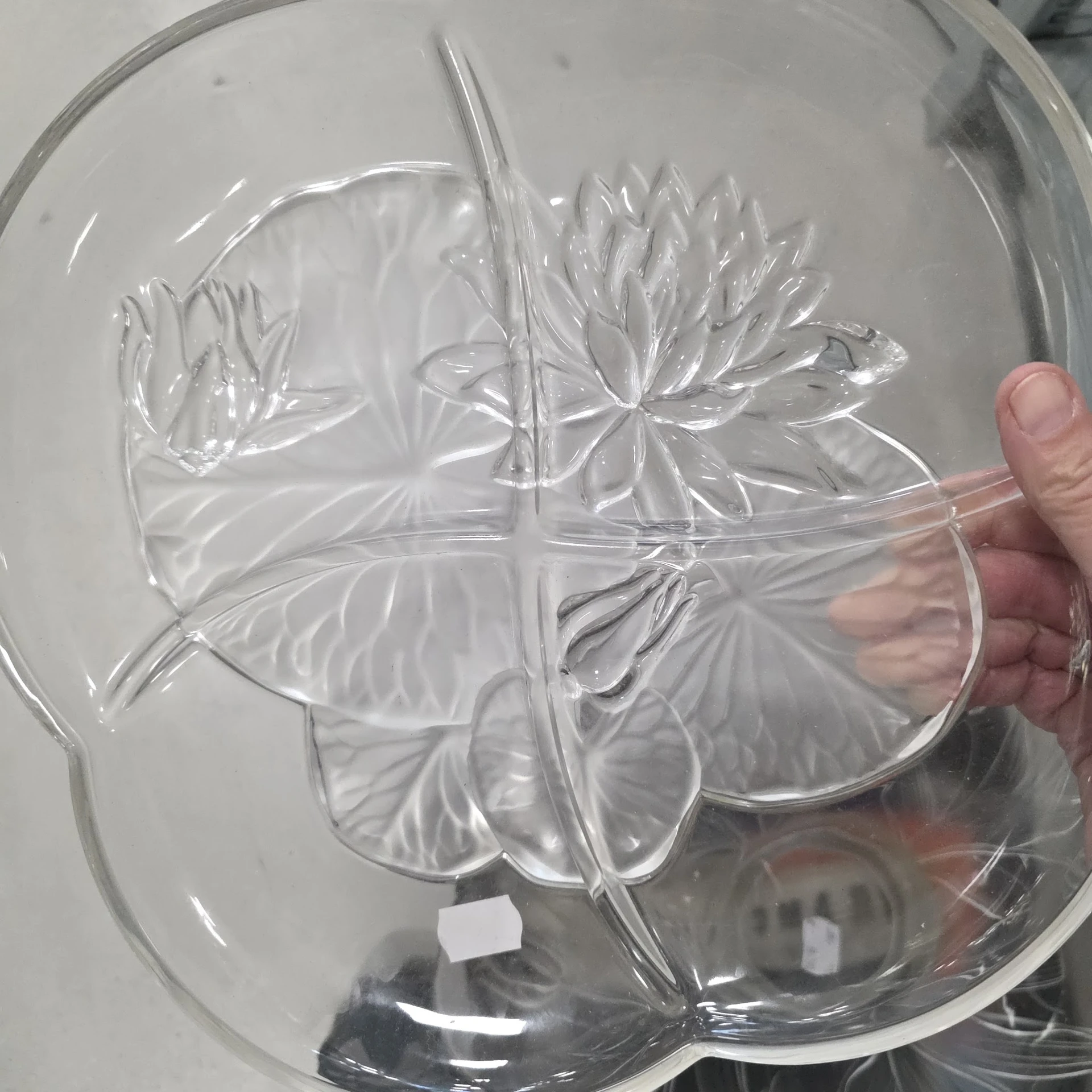 Glazen schaal met reliëfpatroon van bloemen, gehouden in een hand
