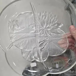Glazen schaal met reliëfpatroon van bloemen, gehouden in een hand