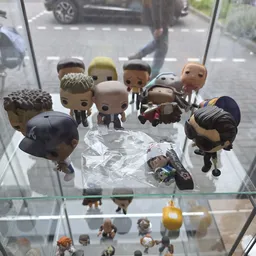 Verzameling Funko Pop-figuren op glazen plank, waaronder personages in verschillende outfits en poses