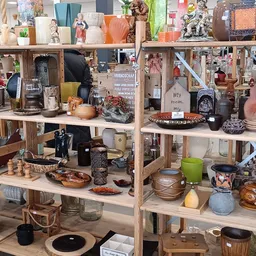 Houten stellingen volgesteld met huishoudwaren, decoratie en diverse tweedehands artikelen in een kringloopwinkel