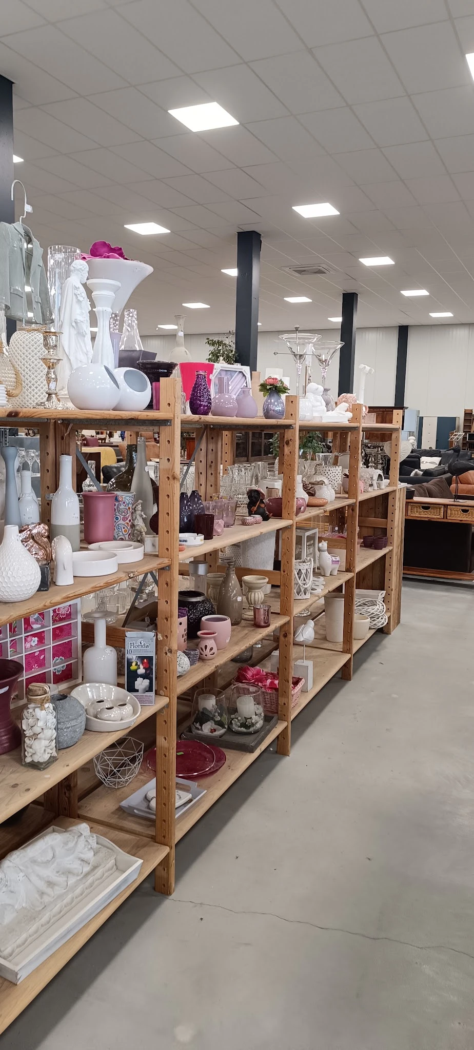 Houten stellingen volgestapeld met huishoudelijke artikelen, decoratie en serviesgoed in diverse kleuren en stijlen