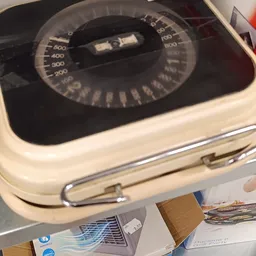 Close-up van een vintage weegschaal met zwarte wijzerplaat en crèmekleurige behuizing