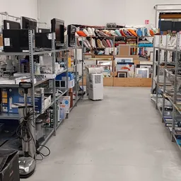 Winkelvloer met stellingen vol elektronische apparaten, boeken, kleding en diverse goederen in een kringloopwinkel