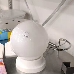 Witte bolvormige lamp met prijssticker op voet, staande op witte ondergrond
