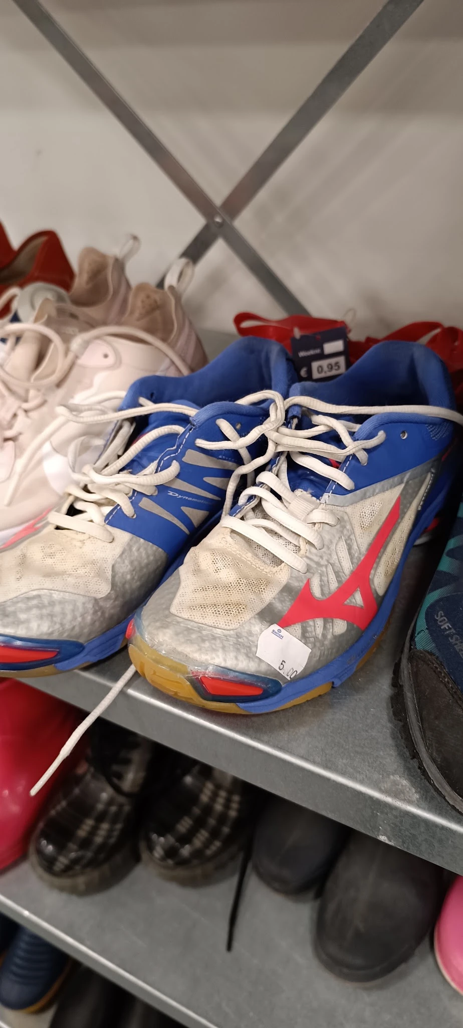 Paar tweedehands sportschoenen in blauw, wit en rood met witte veters, close-up.