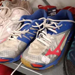 Paar tweedehands sportschoenen in blauw, wit en rood met witte veters, close-up.