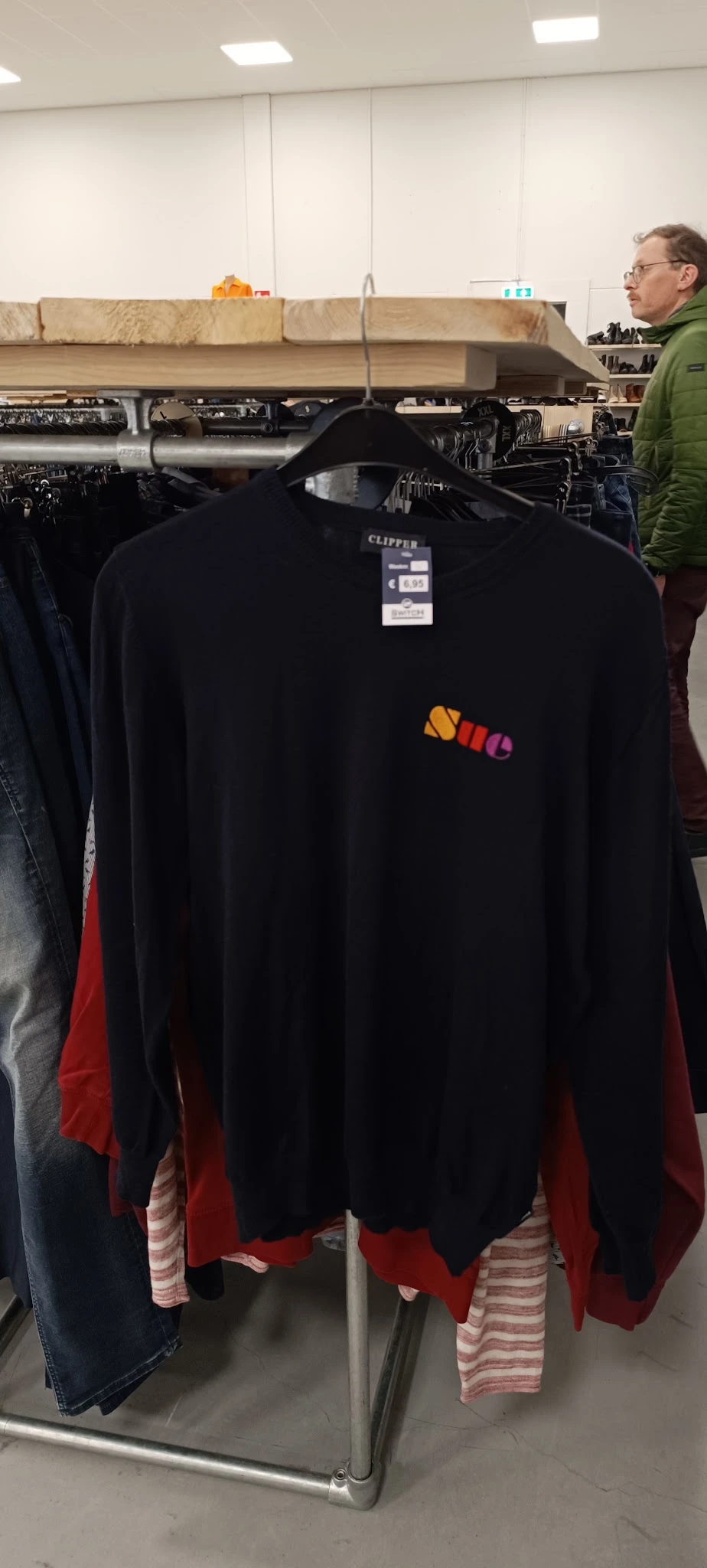 Zwart longsleeve shirt met gekleurde logoprint op de borst, op een kledinghanger